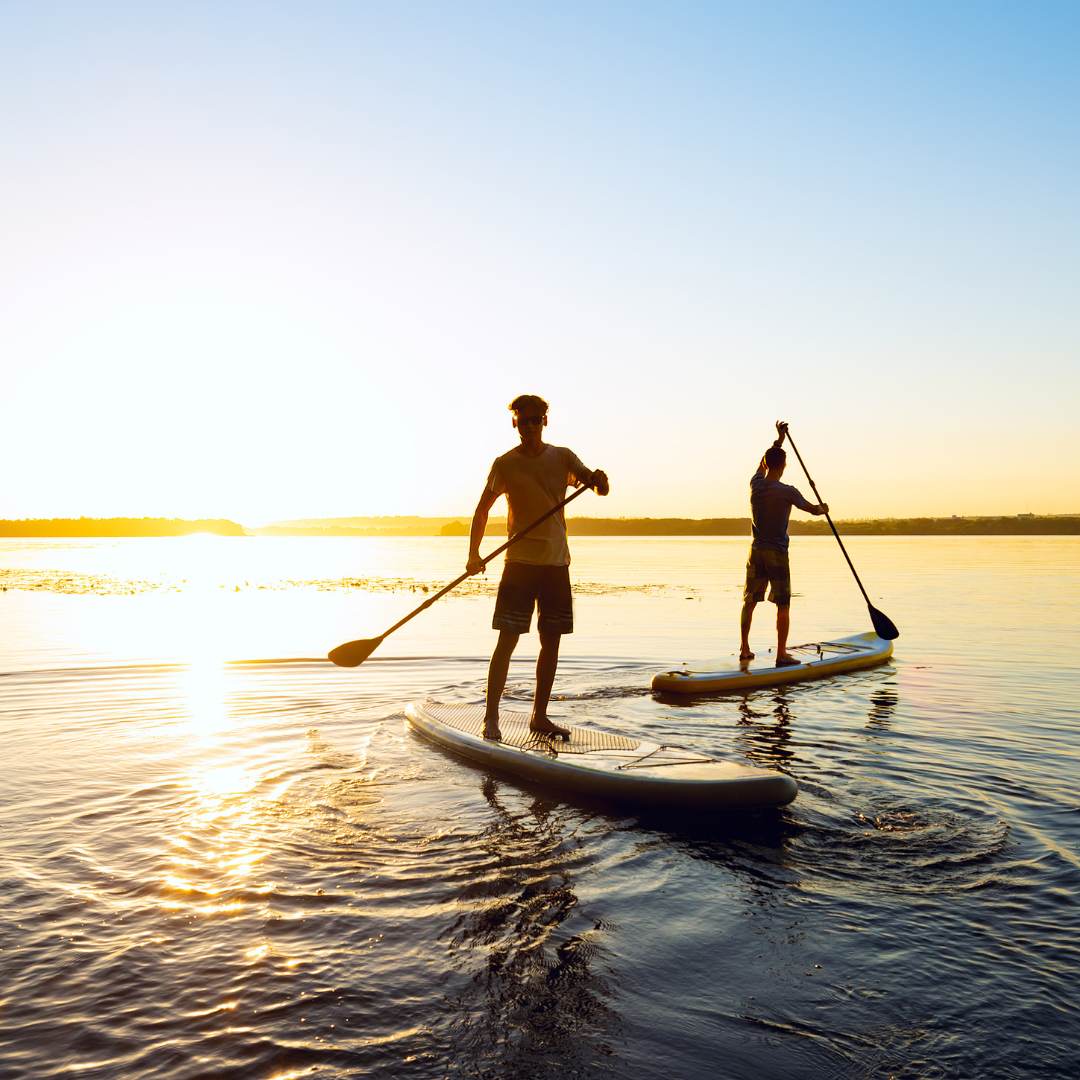 Dos jovenes realizando Paddle Surf al amanecer en Barcelona